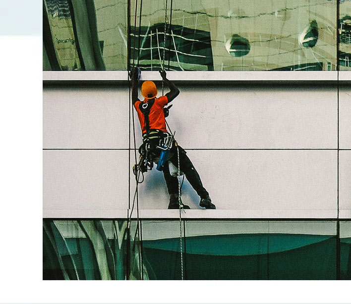 Das Bild zeigt einen Profi-Glasreiniger bei der Fensterreinigung einer Fensterfront.